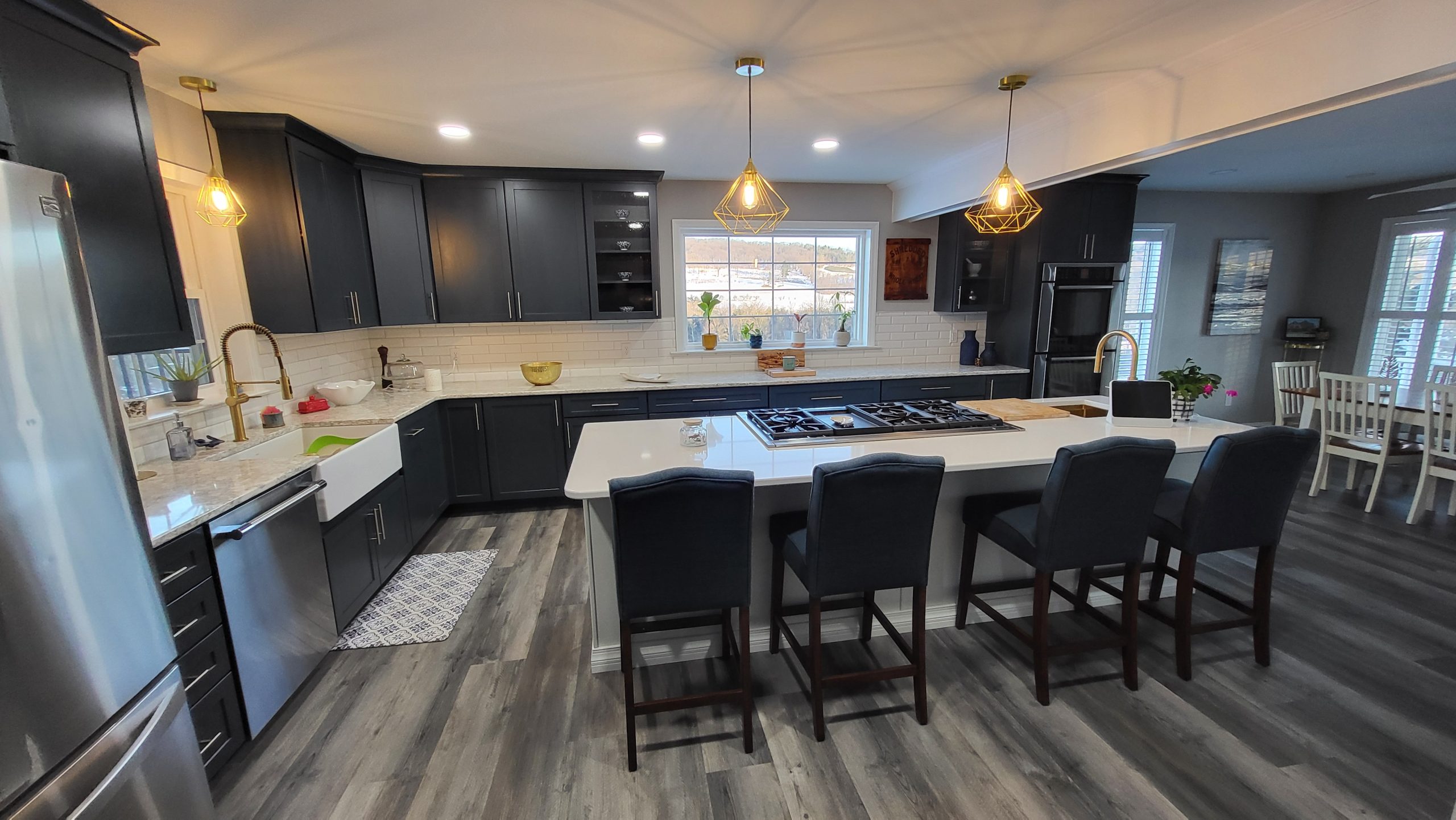 Modern Schuylkill County kitchen with dark cabinetry, large island with barstool seating, and gold pendant lights.